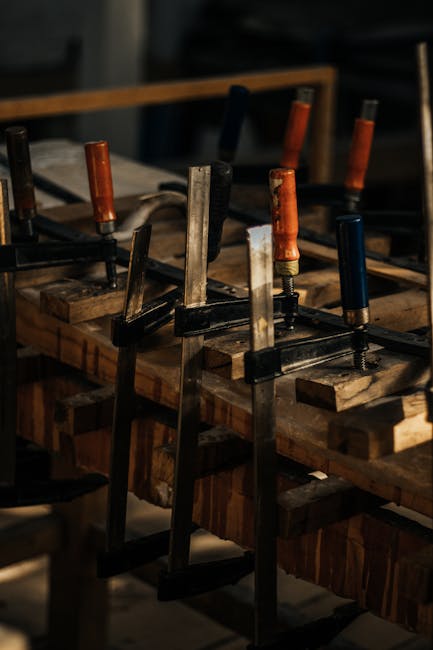 Detailed view of C-clamps on wooden planks in a craftsman's workshop setting.