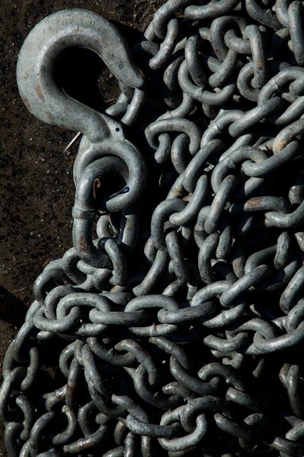 Detailed shot of an intertwined iron chain with a large metal hook, perfect for industrial or nautical themes.