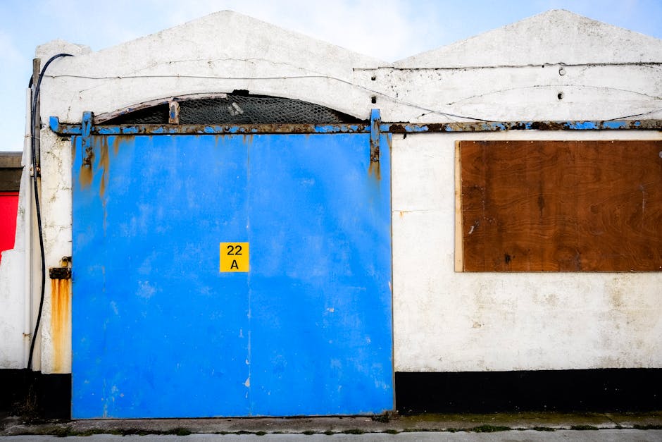 A vivid blue sliding door on an old industrial building with weathered textures and a rustic look.