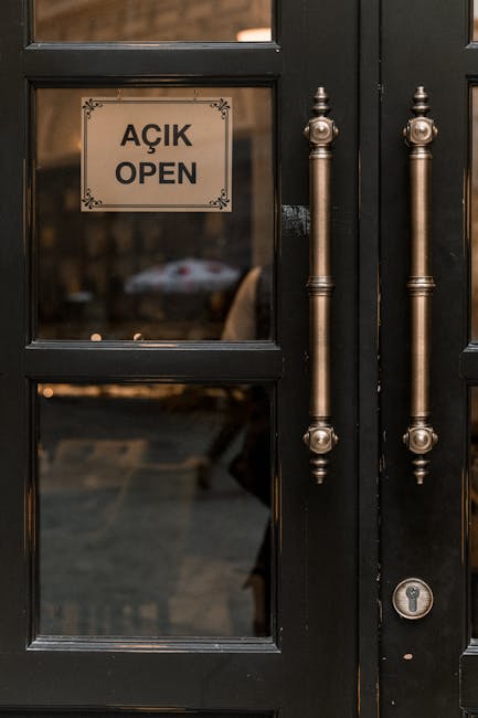 Close-up view of double doors with an 'Açık Open' text sign, reflecting a cozy street.