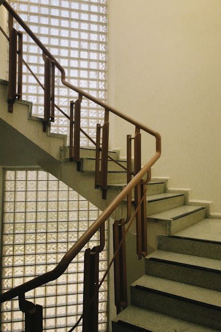 Elegant indoor staircase with metal railings and a glass brick wall, featuring clean lines and a minimalist design.