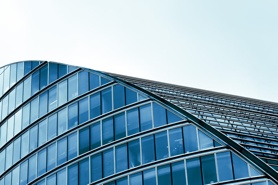 Sleek modern architecture with curved glass facade in an urban setting.