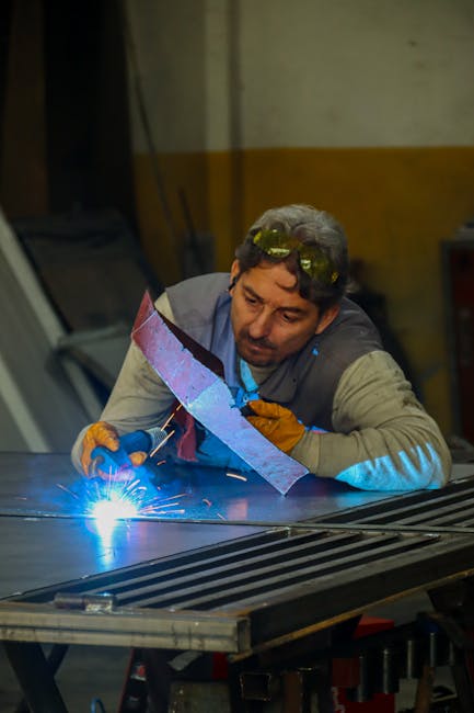 An adult man welding metal indoors with sparks flying, showcasing concentration and skill.