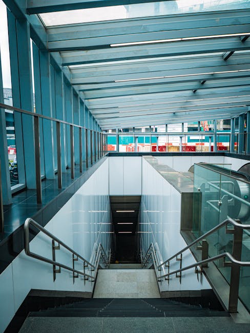 Bright subway entrance with a sleek glass roof and descending stairs.