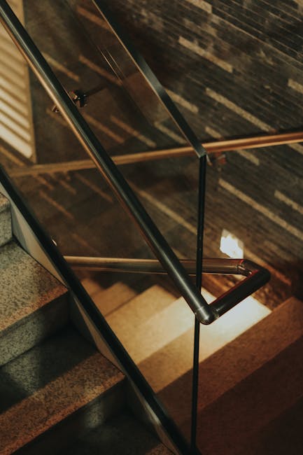 Close-up view of a modern indoor staircase with sleek metal and glass handrails.
