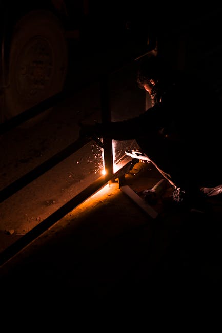A solitary welder works meticulously at night, casting sparks and shadows.