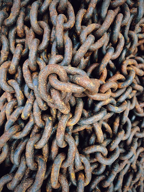 Close-up view of intertwined rusted chains creating a complex iron pattern.