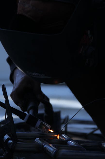 A welder skillfully works with metal using a welding torch in an industrial setting.