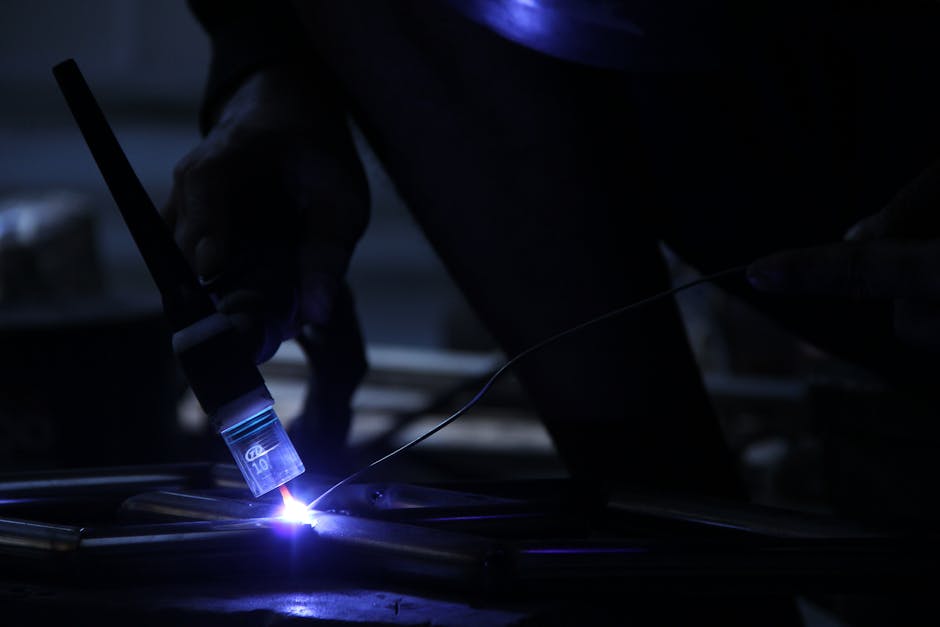 Close-up shot of a welder working in a dimly lit industrial environment.