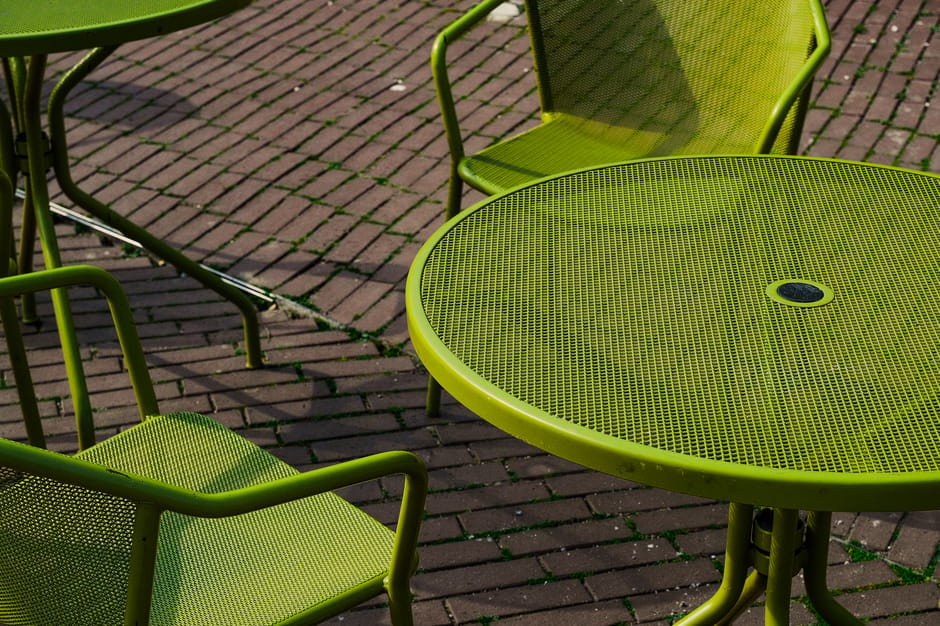 Green iron chairs and table on pavement in sunny Istanbul outdoor cafe.
