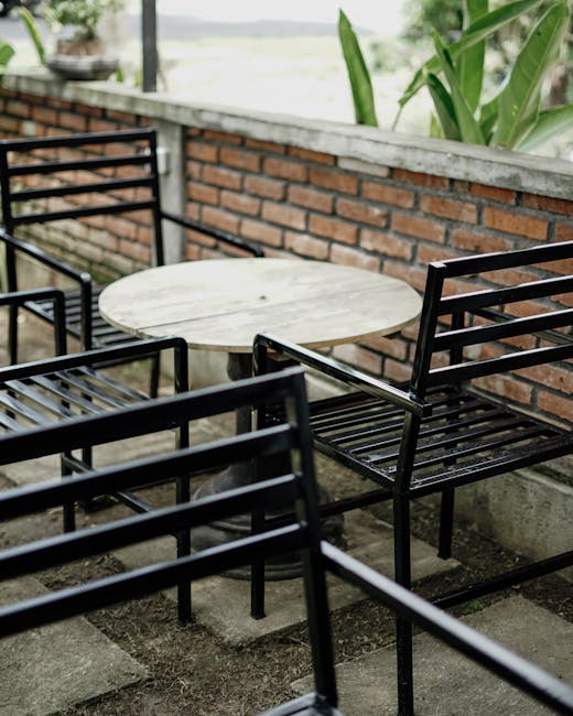 Cozy outdoor patio with black metal chairs and round wooden table, inviting ambiance.