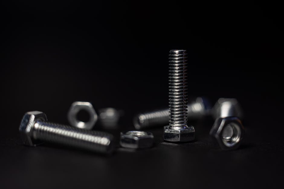 Detailed close-up of metal screws and nuts with a dark background highlighting textures and shapes.