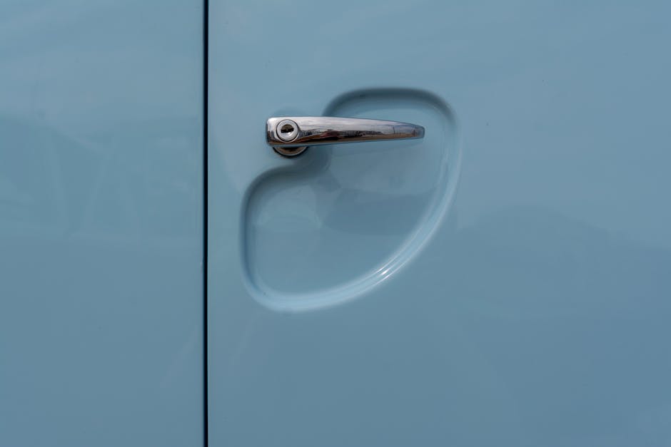 Elegant close-up shot of a metallic car door handle on a vintage blue vehicle.