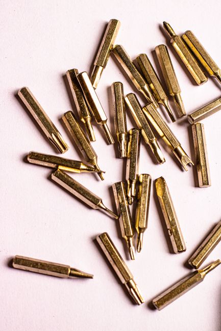 Detailed view of golden drill bits scattered over a white background, perfect for DIY and industry themes.