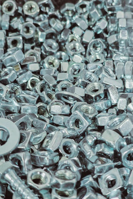 Close-up view of a pile of silver metal nuts and bolts with detailed textures.