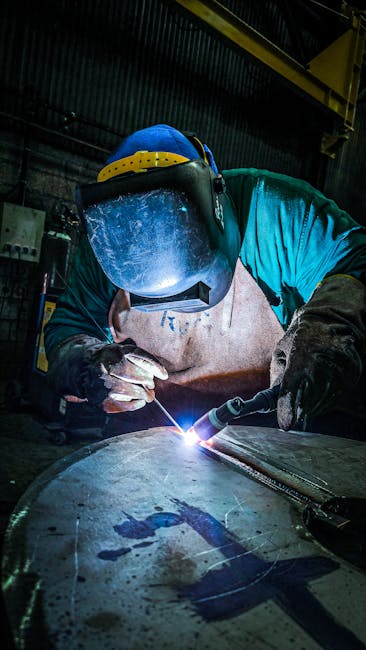Focused welder at work, sparks flying, in an industrial setting with protective gear.