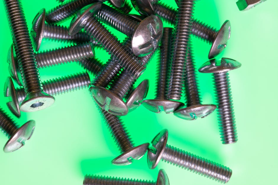 High-impact image of metallic screws scattered on a vibrant green surface.