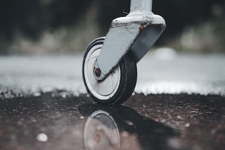 A detailed view of a castor wheel reflected in a puddle on a wet surface, capturing texture and motion.