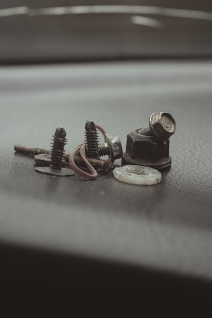 Detailed close-up of various metal screws and bolts on a textured surface, ideal for industrial themes.
