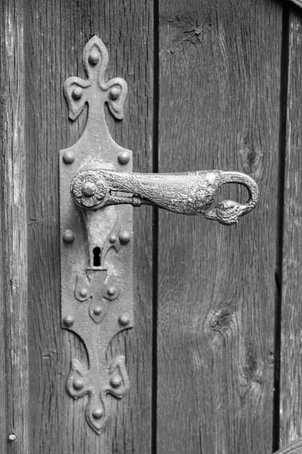 Detailed view of a vintage iron handle on a wooden door.