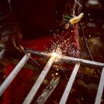 Close-up of a welder creating sparks while working on metal fabrication.