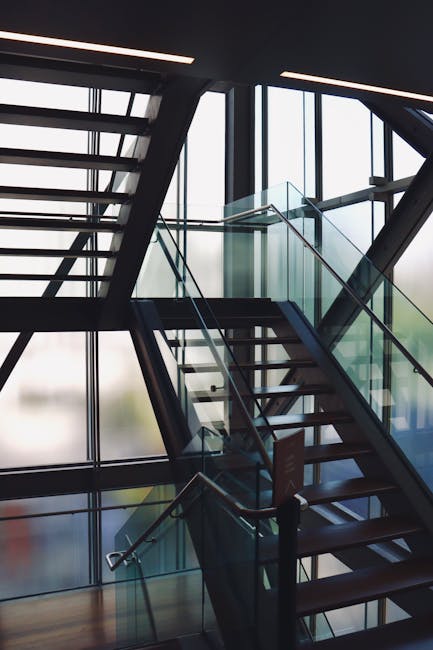 A contemporary glass staircase design within an urban architectural interior, featuring light reflection.