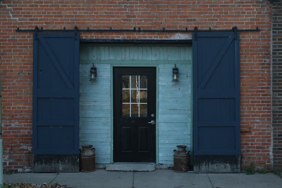 Rustic brick building facade with symmetrical blue wooden sliding doors and vintage metal accents.