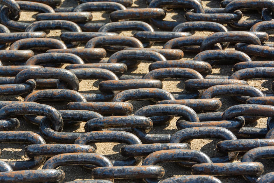 Detailed view of rusty metal chains arranged outdoors in sunlight.