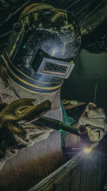Professional welder wearing safety gear performing TIG welding on steel in a Brazilian factory.