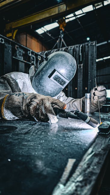A skilled welder wearing protective gear performs welding in an industrial setting.