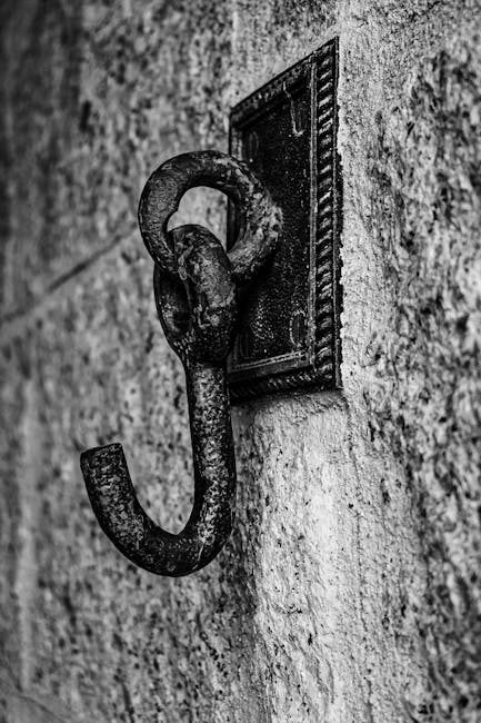 Black and white photo of a rustic metal hook fixed to a stone wall in Ilhabela, Brazil.