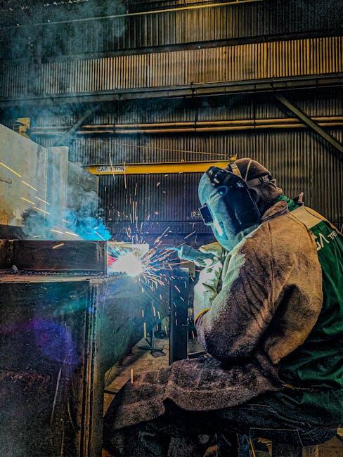 A welder in Brazil is focused on welding steel in an industrial setting.