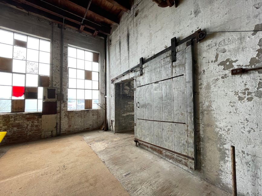 Rustic industrial space with large windows and a steel sliding door.