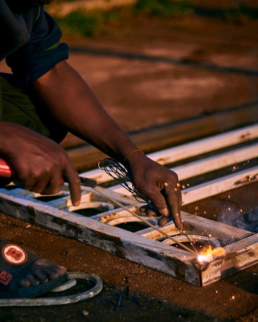 A welder performing metalwork on a gate with sparks flying, captured during dusk.