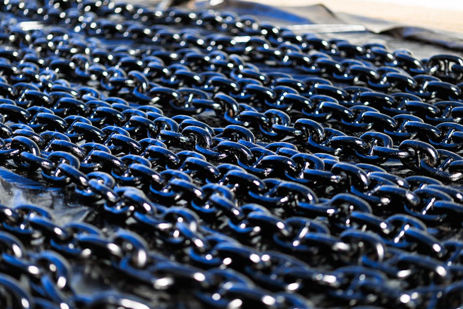 Detailed view of shiny industrial metal chains arranged outdoors, showcasing texture and metallic quality.