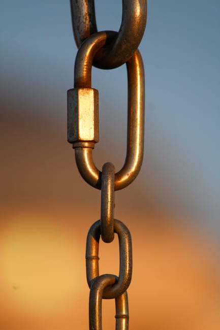 A detailed view of a metal chain link against a blurred background, emphasizing strength and connection.