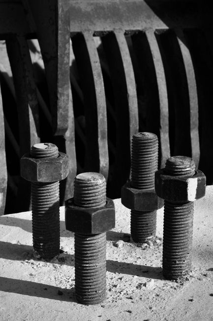 Black and white photo of industrial bolts casting shadows.
