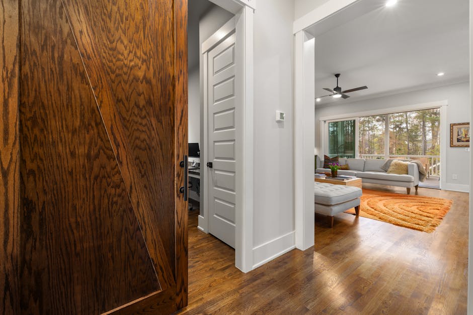 Spacious living room with large windows and wooden sliding door, featuring a cozy sofa and vibrant decor.