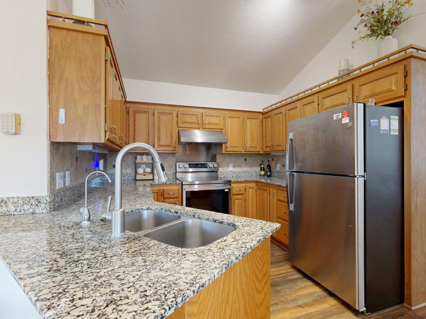 Spacious kitchen featuring granite countertops, stainless steel appliances, and wooden cabinetry.