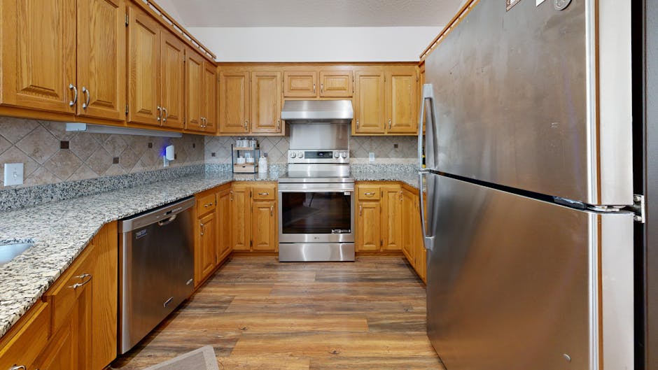 A well-lit kitchen featuring stainless steel appliances and wooden cabinets.