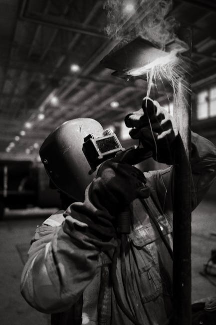 A skilled welder works with sparks flying in a dimly lit factory, illustrating industrial craftsmanship.