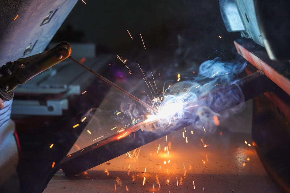 Close-up of a welder at work with sparks and smoke in an industrial setting.