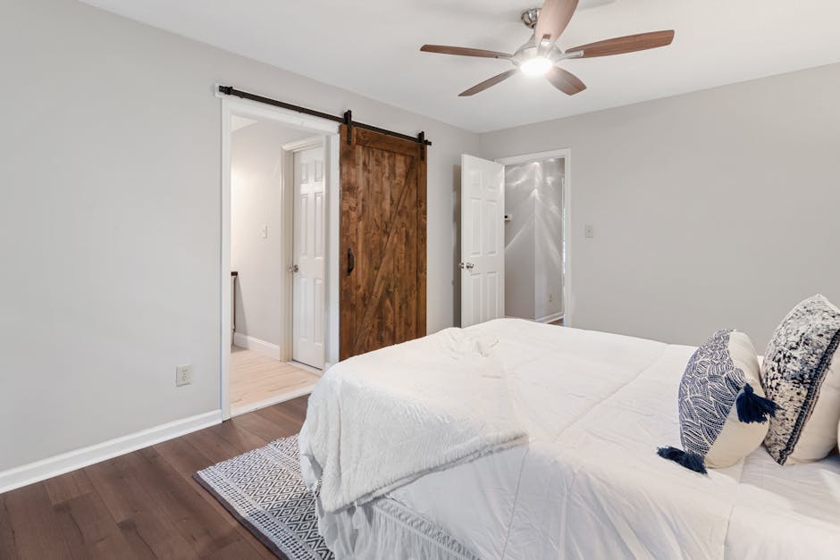 Cozy and stylish bedroom featuring a wooden sliding door and sleek ceiling fan, perfect for a contemporary home decor.