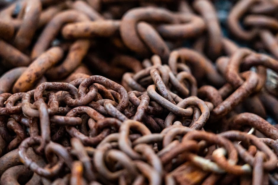Detailed close-up image showing intertwined rusty steel chains, highlighting texture and decay.