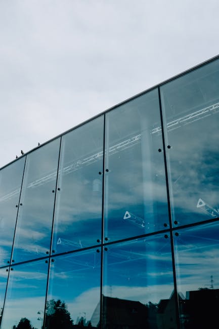 Contemporary multistory office building exterior with glass walls under gray sky in modern city