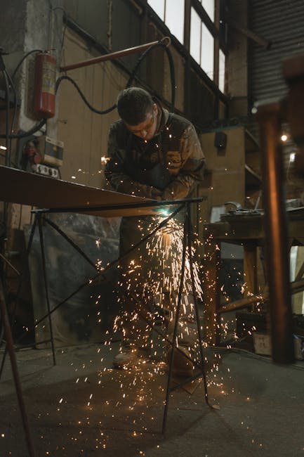A professional welder using safety equipment and tools to work on metal fabrication.