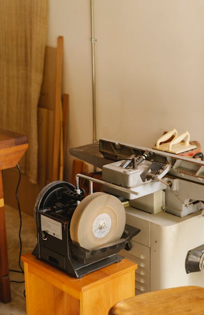 Grinding machine with sharp metal wheels near wall and cable in workroom in daylight