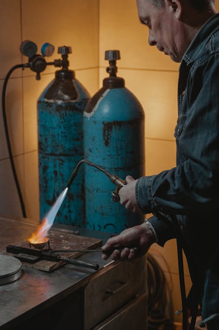 A jeweler skillfully uses a torch for metal melting in a workshop setting.