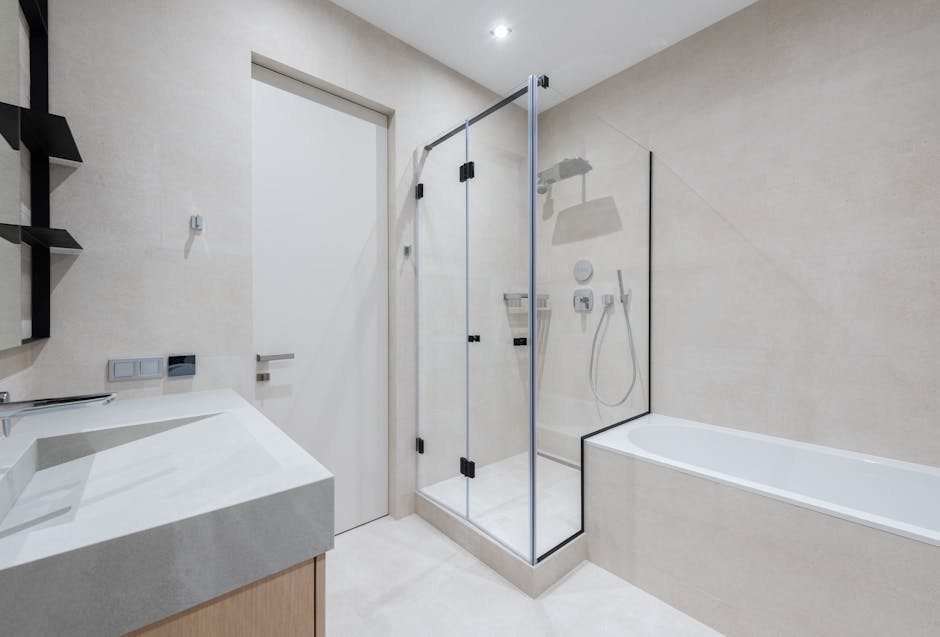 Interior of modern light bathroom with bathtub and shower next to sink with cabinet near door