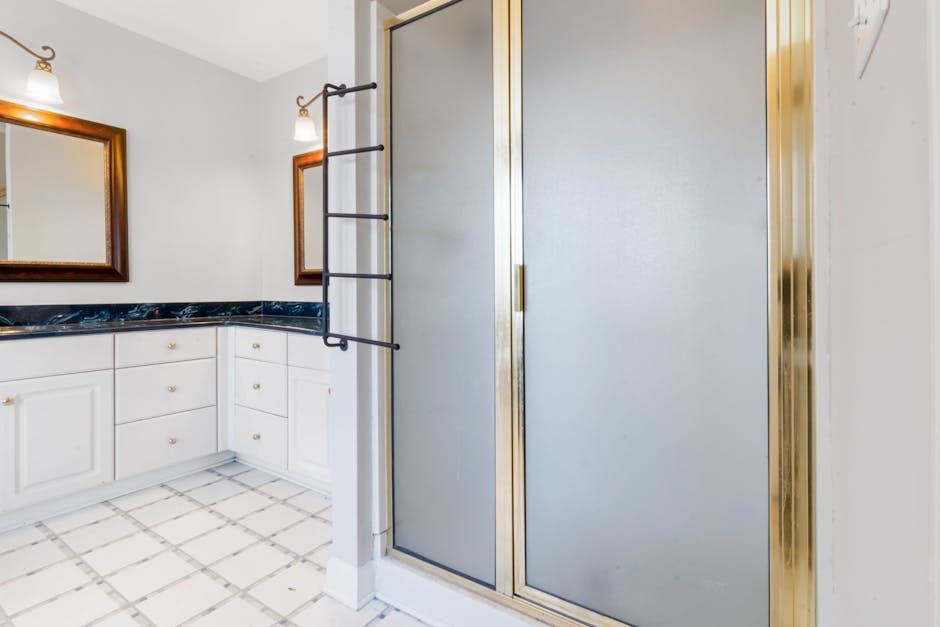Elegant bathroom featuring a shower with gold trim and marble countertops, highlighting modern interior design.